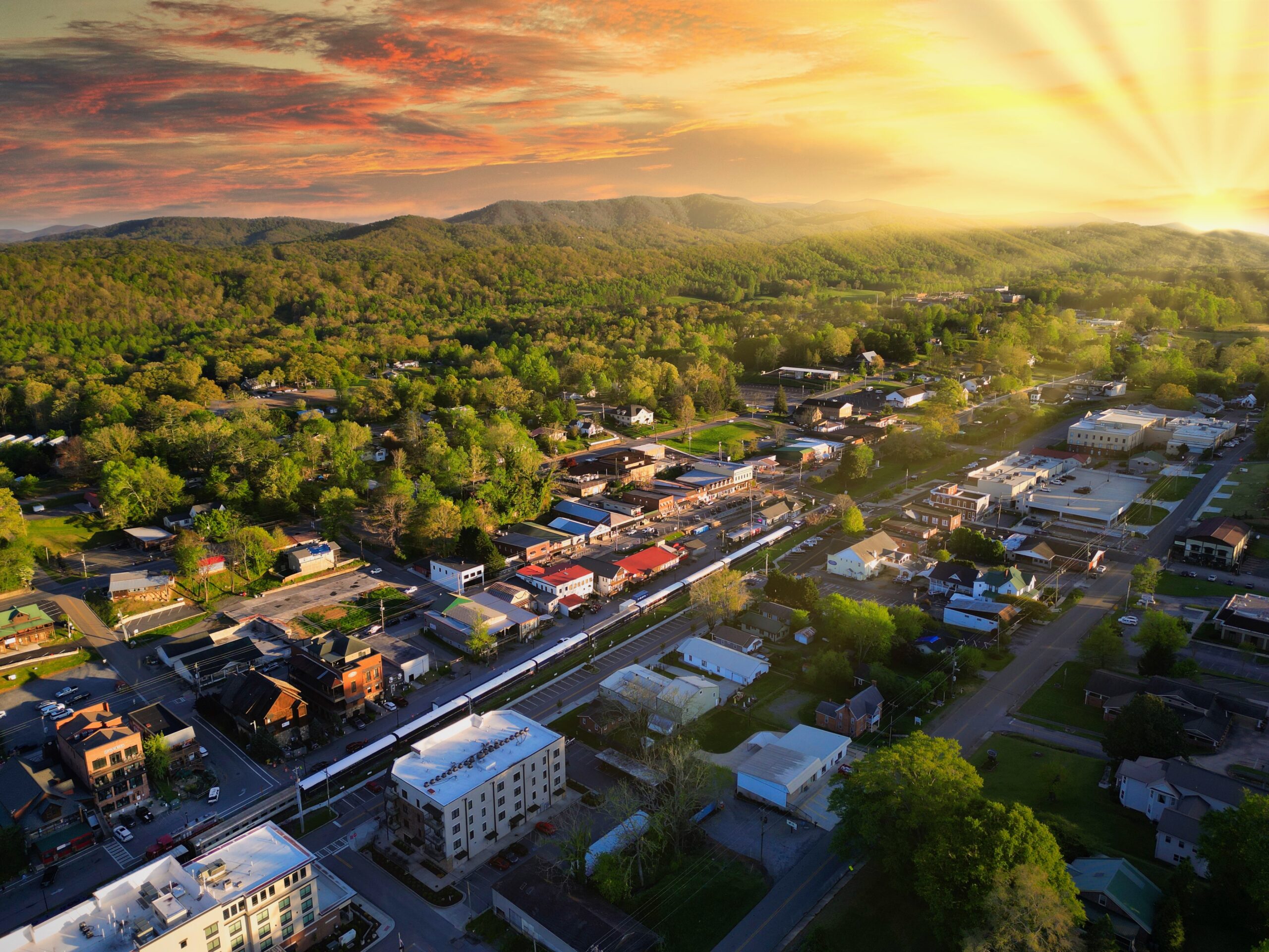 Aerial view of downtown Blue Ridge, Georgia at sunset, with the railroad through town and wooded ridgelines of Fannin County behind it