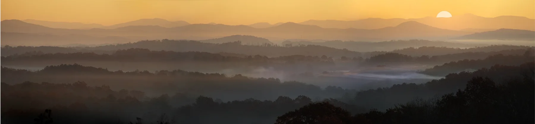 Layered mountain ridgelines in morning fog at sunrise