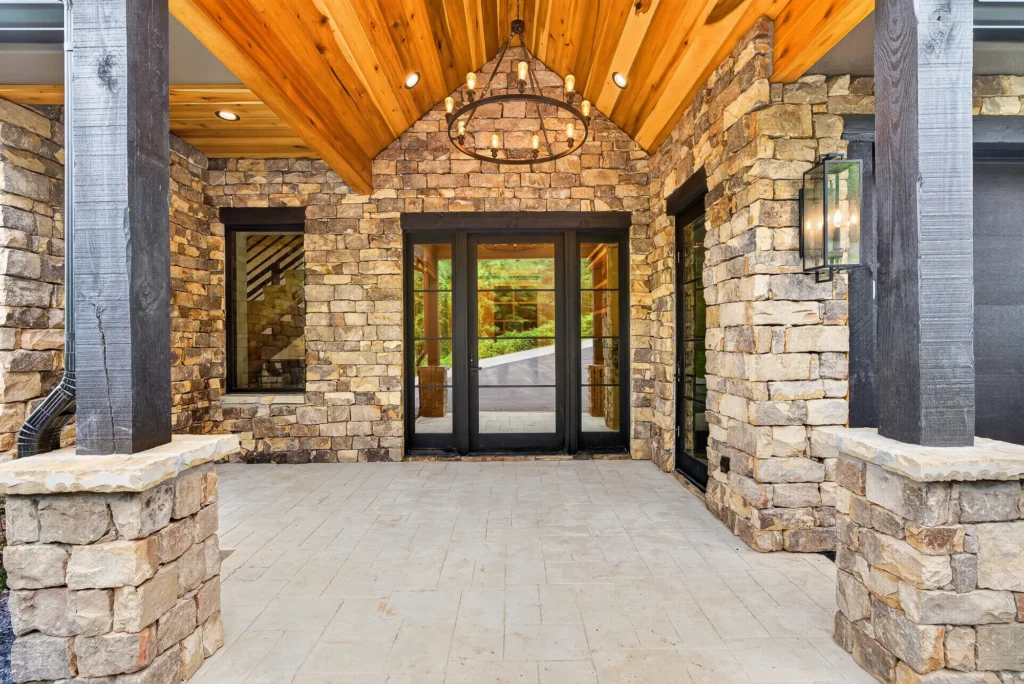 Stone entry porch with glass front doors and a chandelier