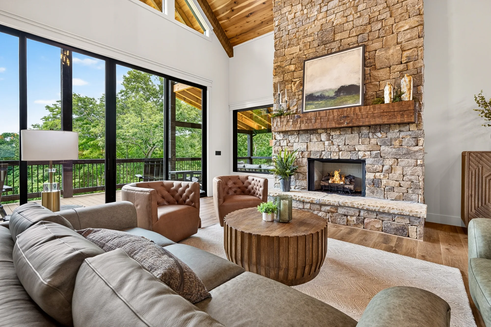 Staged living room with a floor-to-ceiling stone fireplace