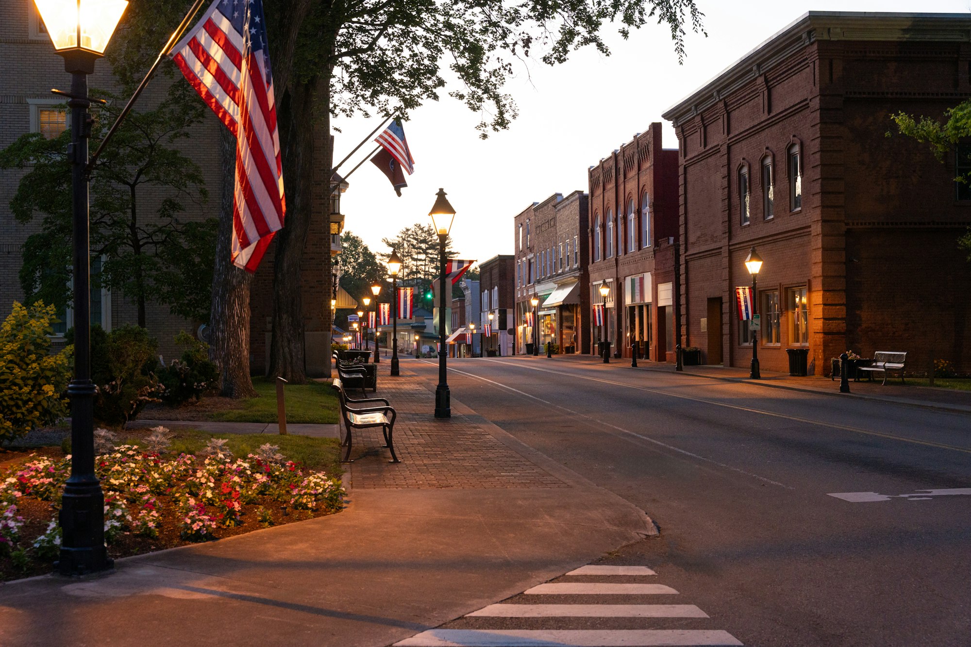 Historic small-town main street at dusk with lamp posts and flags