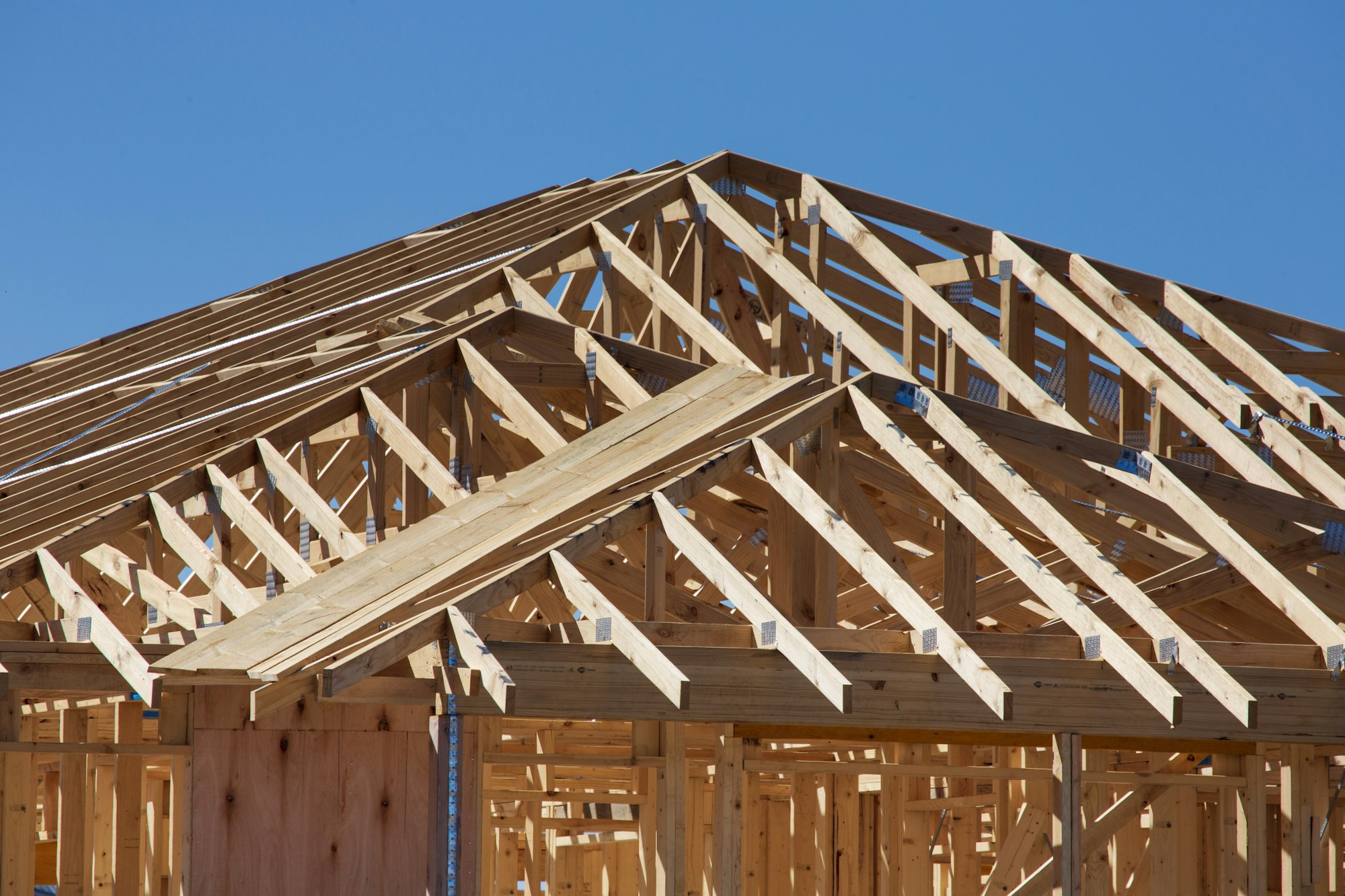 Wood roof trusses of a new home under construction against a blue sky