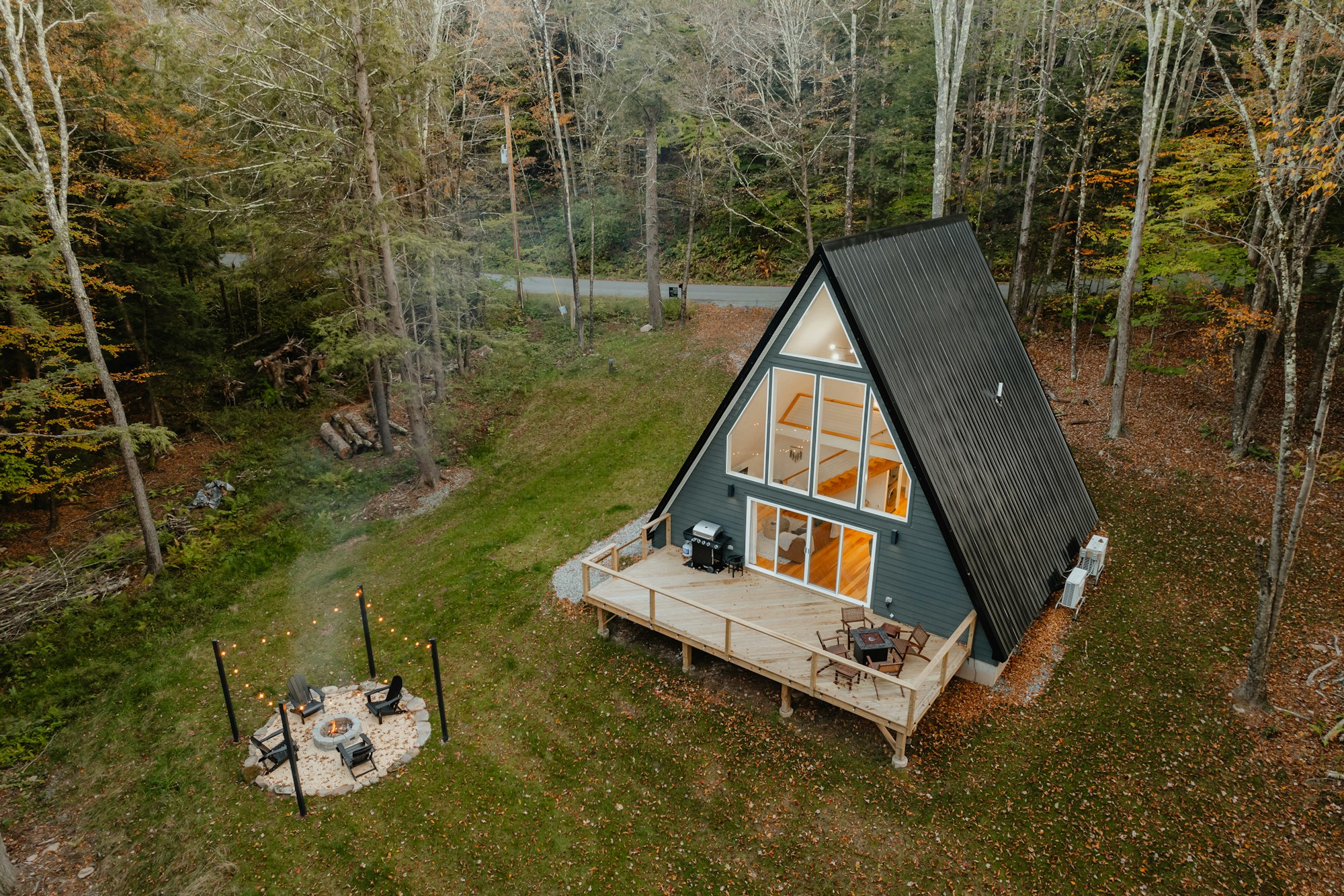 A-frame cabin with deck and firepit clearing in the autumn woods