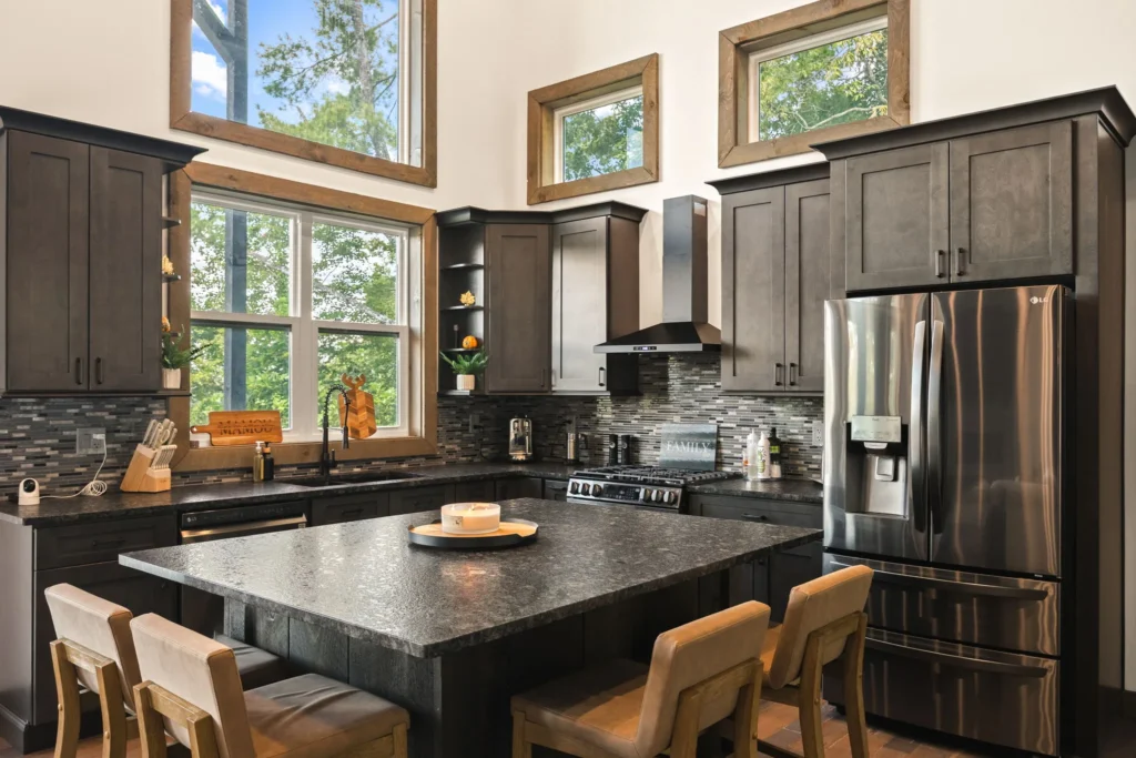 The kitchen in full — dark stained cabinetry, stone counters, vent hood and seating for four at the island.