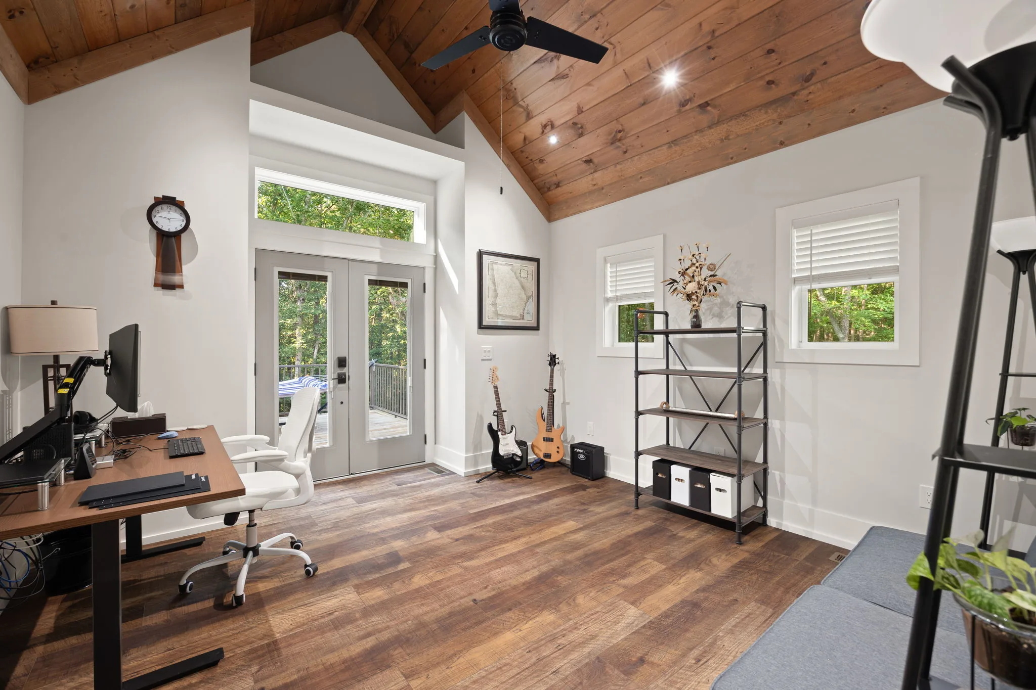 First-floor bedroom staged as home office: stained tongue-and-groove ceiling, French door to the deck