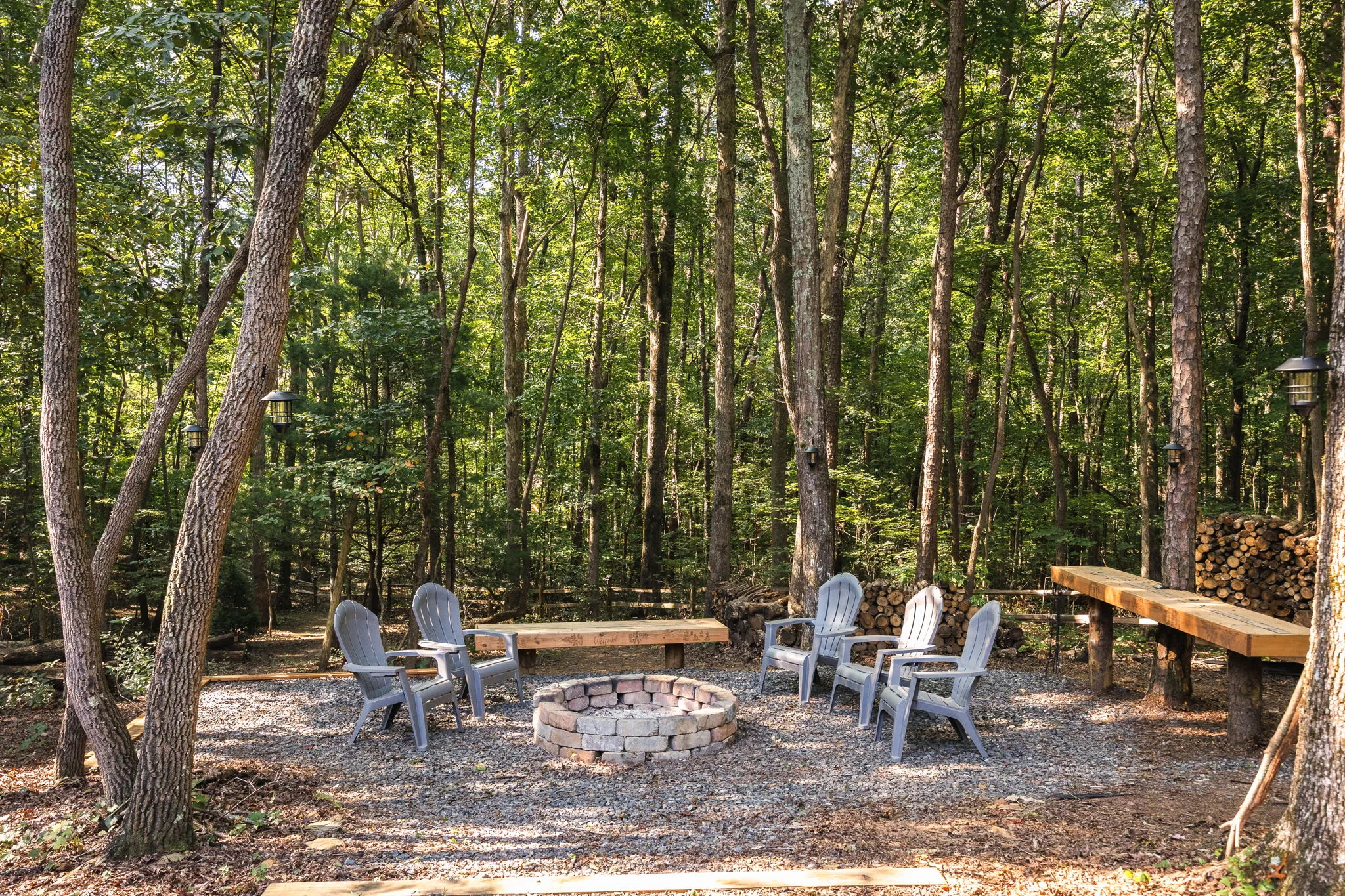 Stone fire pit with custom wood benches, surrounded by woodland