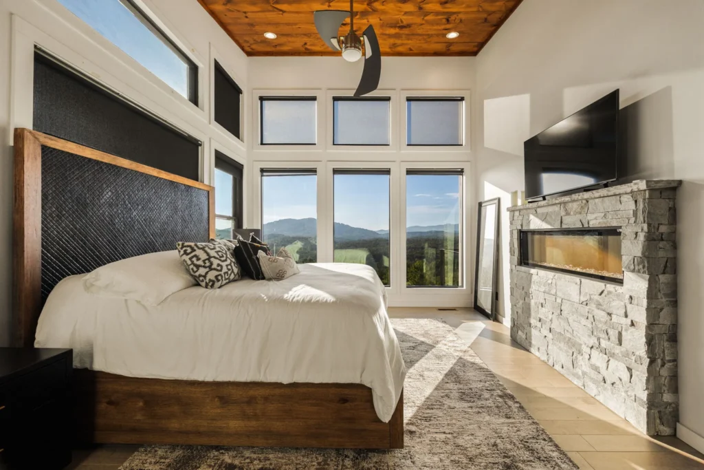 Primary suite with a stone fireplace feature wall and a wall of mountain windows