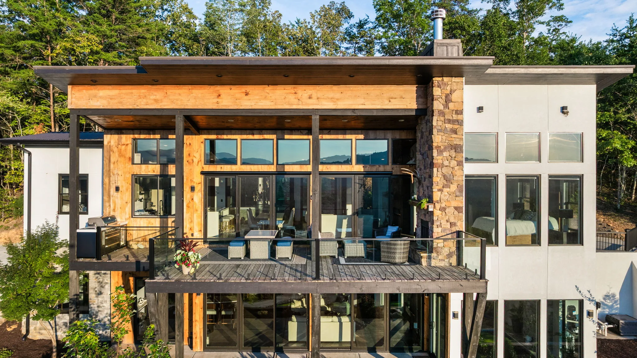 Elevated view of the rear facade, deck, exposed beams and stone chimney
