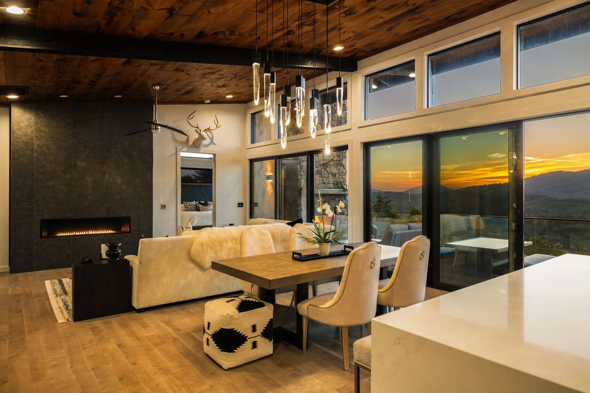 Great room at sunset, fireplace lit and the ridge line glowing through the sliders