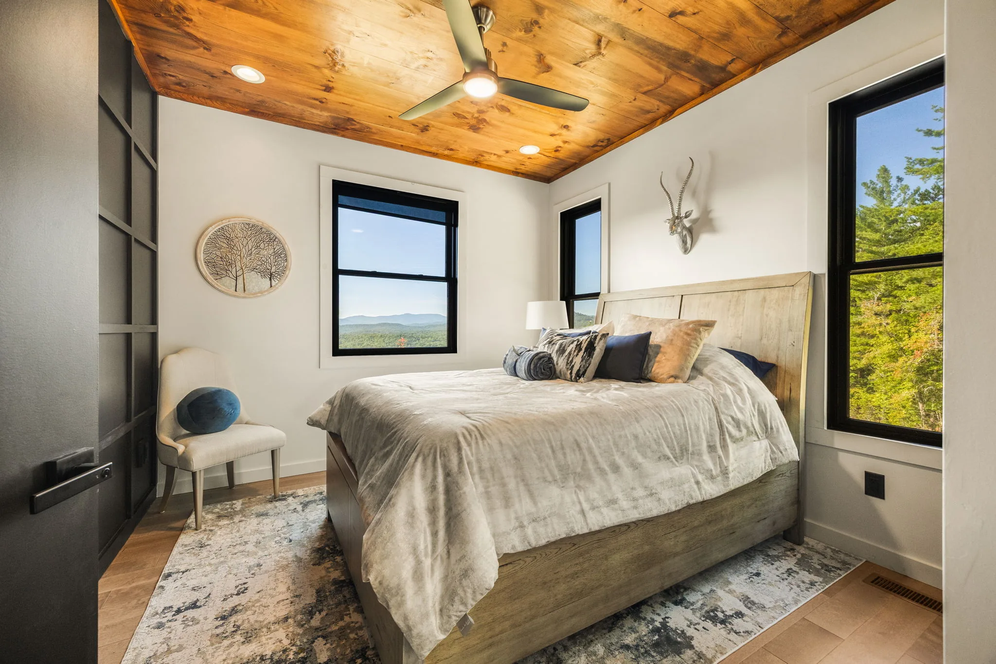 Second bedroom with a wood platform bed and black-frame windows on the view
