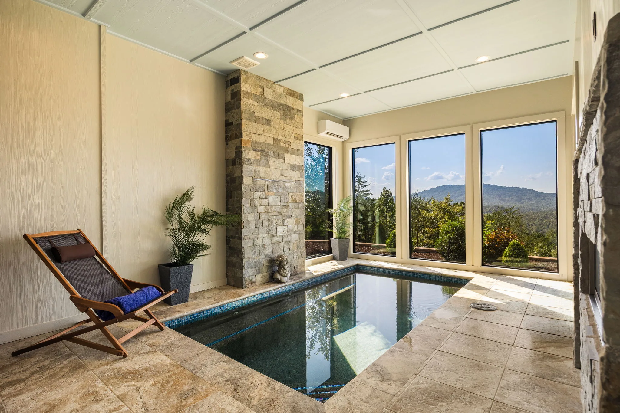Indoor pool in its glass sunroom, travertine deck and stone column