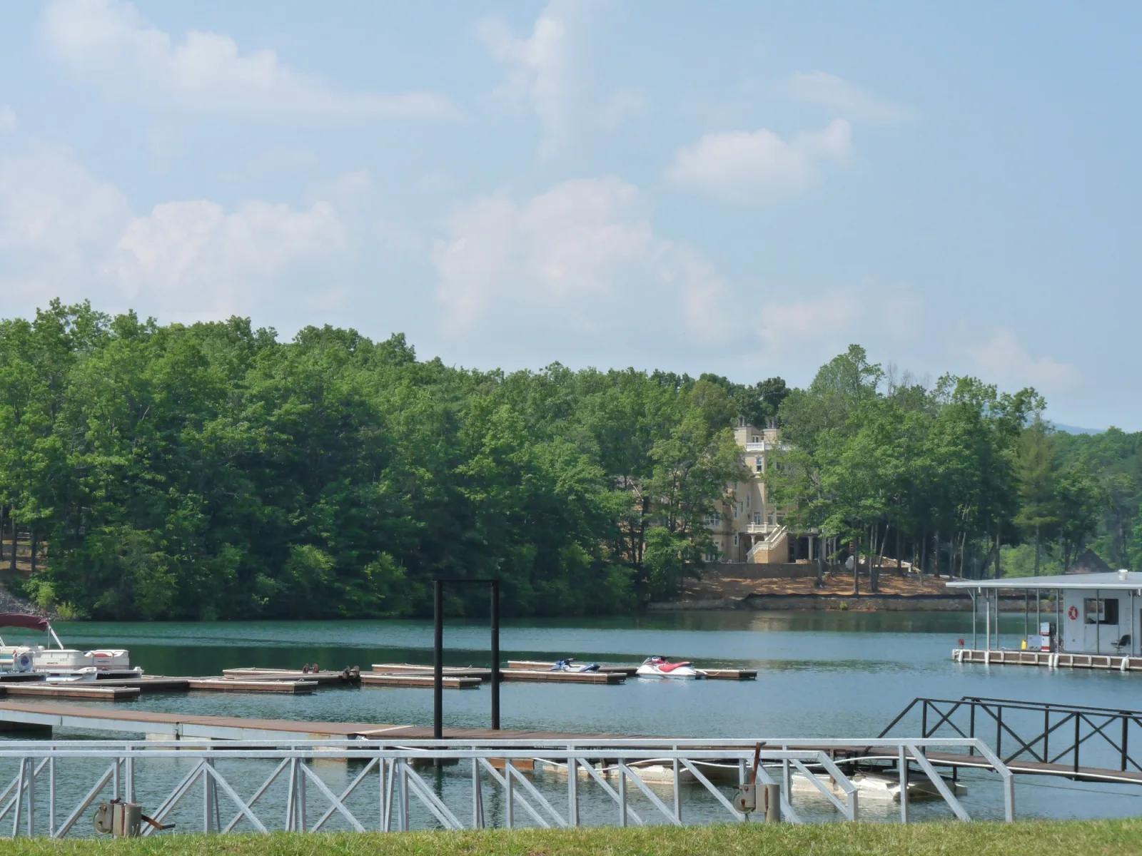 Boat docks and a personal watercraft on Lake Blue Ridge in June, with a lakefront home set back behind a wooded shoreline
