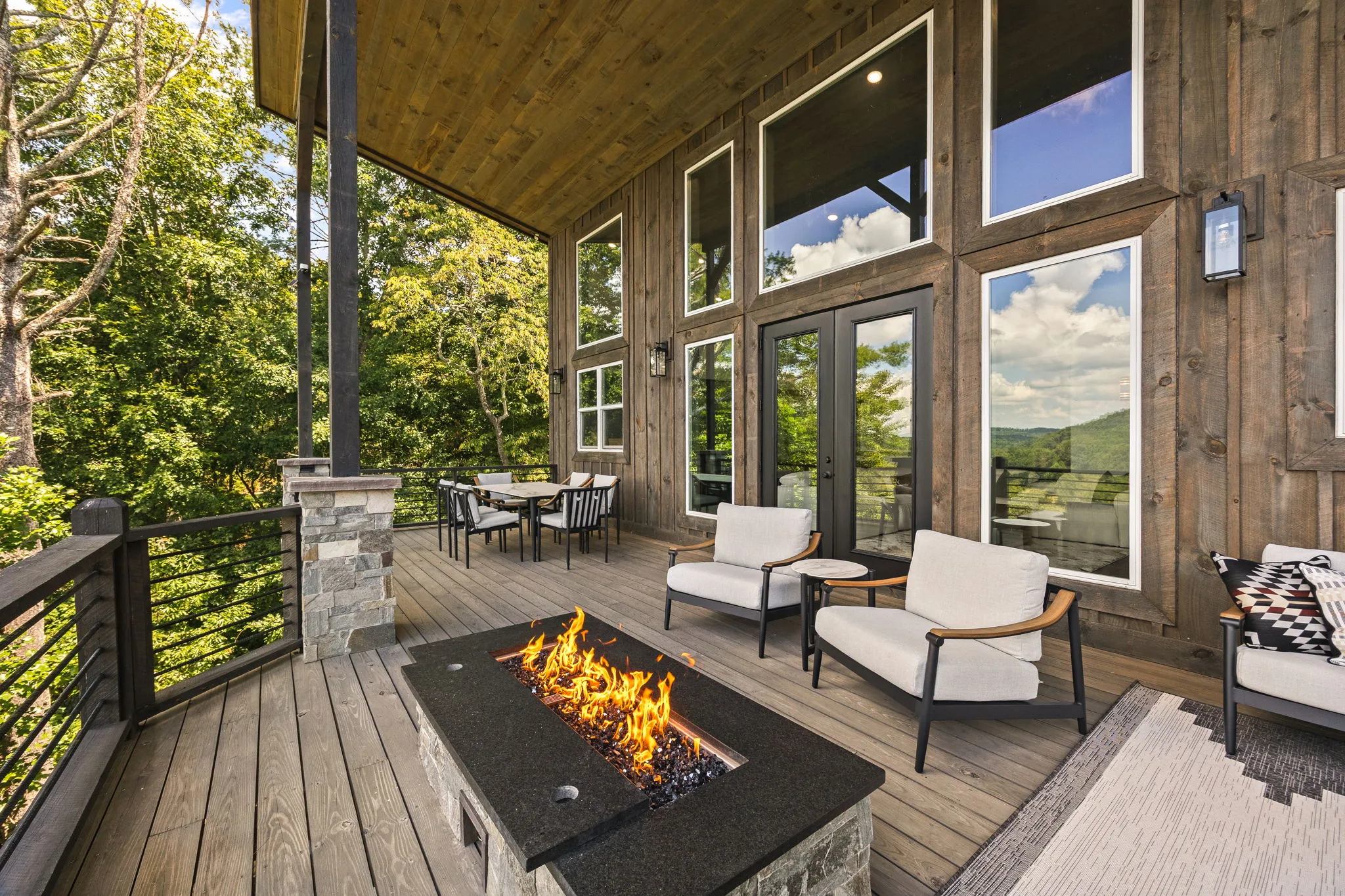 Wide view down the main covered deck with the fire table burning and the mountains stacked behind.