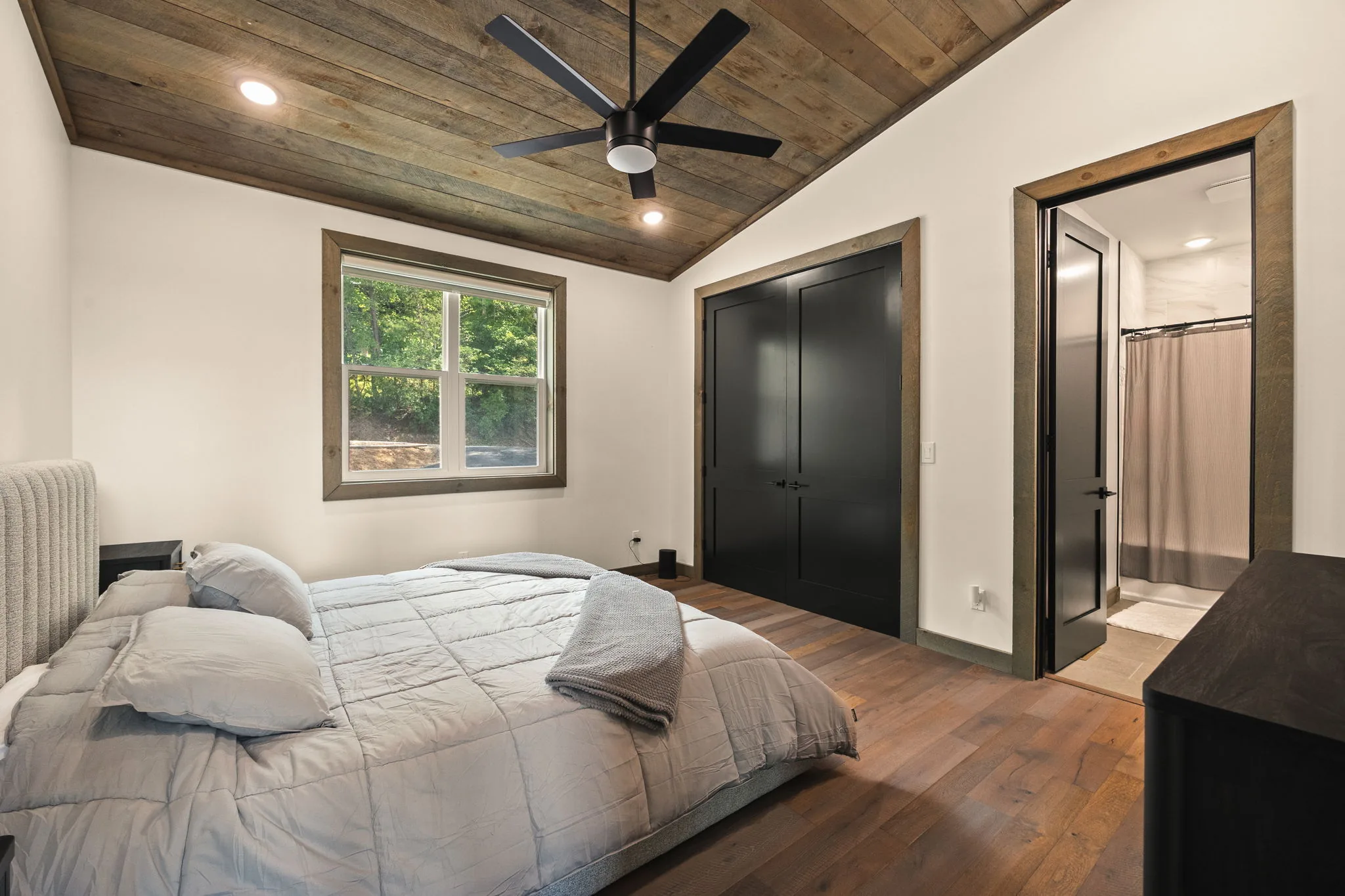 Second bedroom on the main level, with a shiplap vaulted ceiling, ceiling fan and its own ensuite bath.