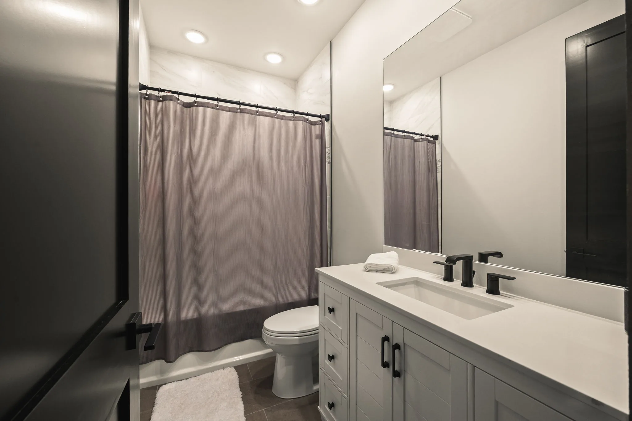 Ensuite bath serving the second bedroom, with a tub-shower and a single vanity.