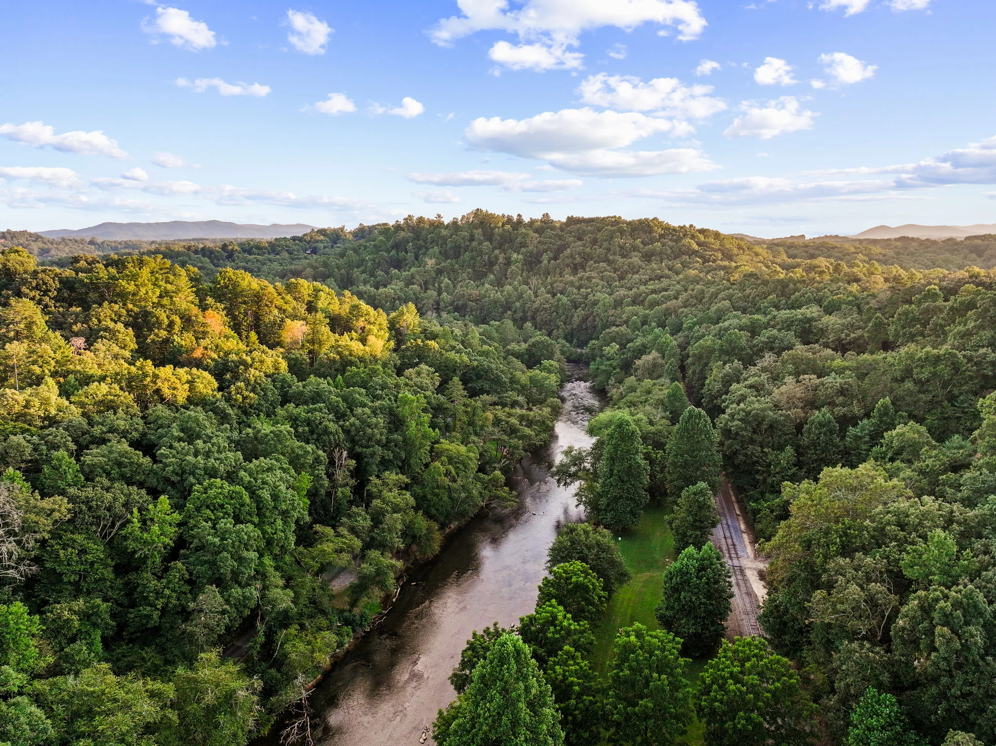 Golden-hour aerial following the Toccoa River through the valley below the property