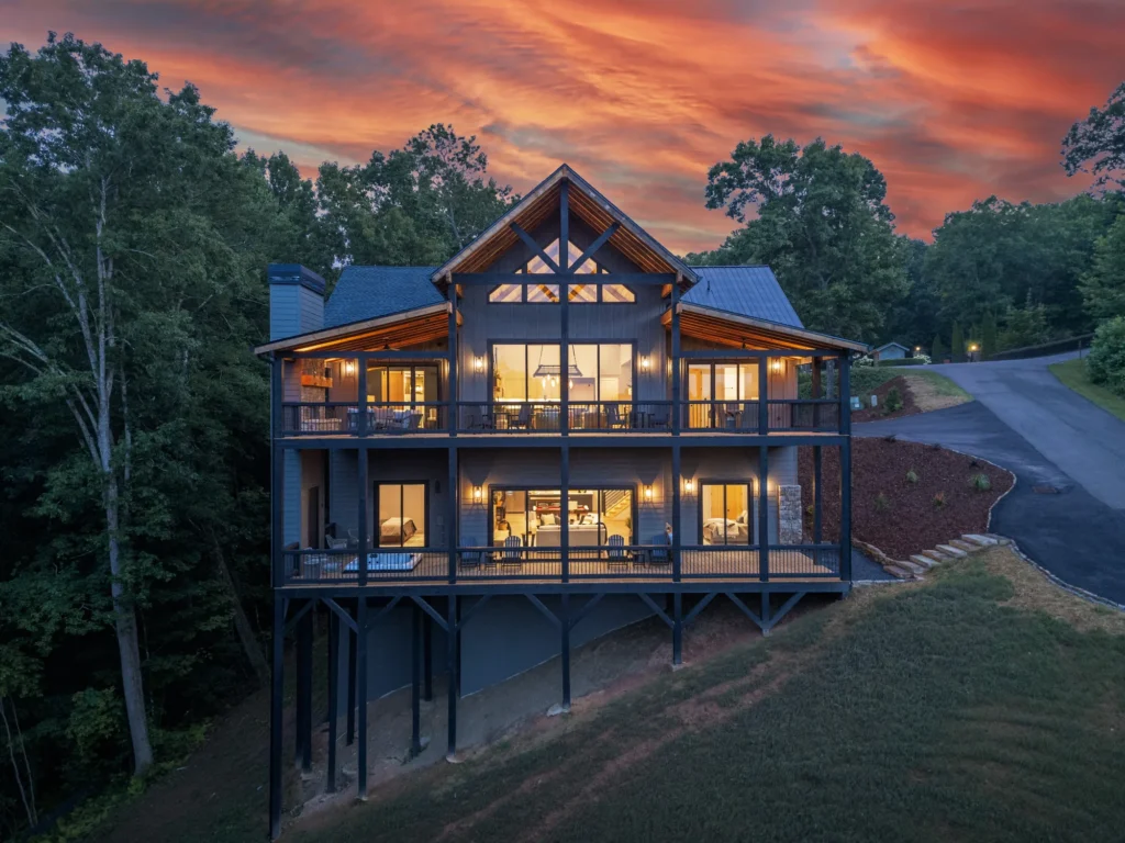 44 Staurolite Mountain Road at twilight, its lighted decks rising three levels above the wooded hillside in Blue Ridge, Georgia
