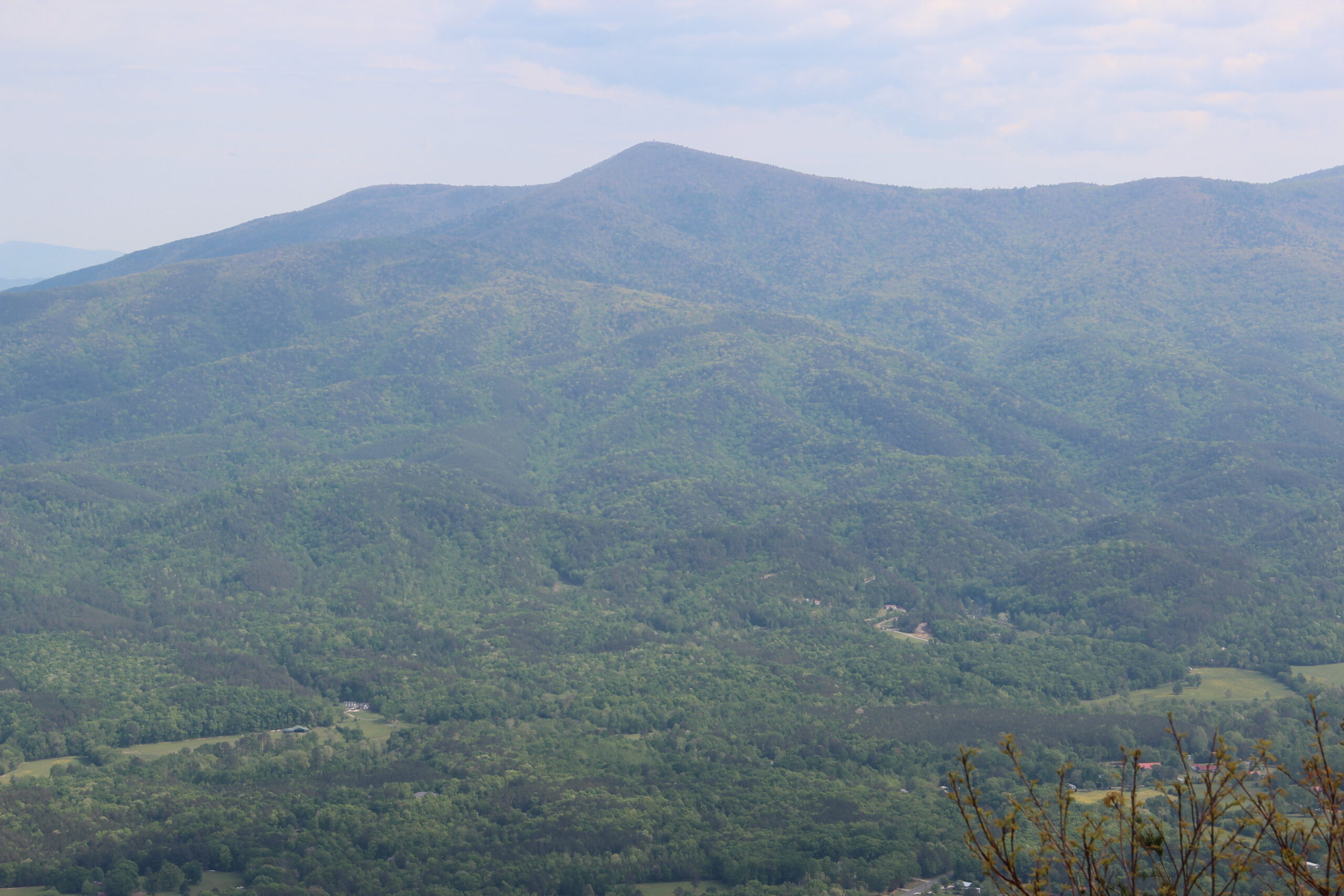 Grassy Mountain rising above a wooded valley with a few scattered homes and pastures, seen from Fort Mountain in Georgia